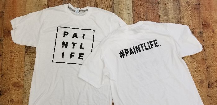 two white t-shirts are sitting on a wooden table