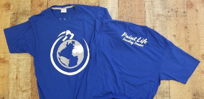 two blue t-shirts are sitting on a wooden table