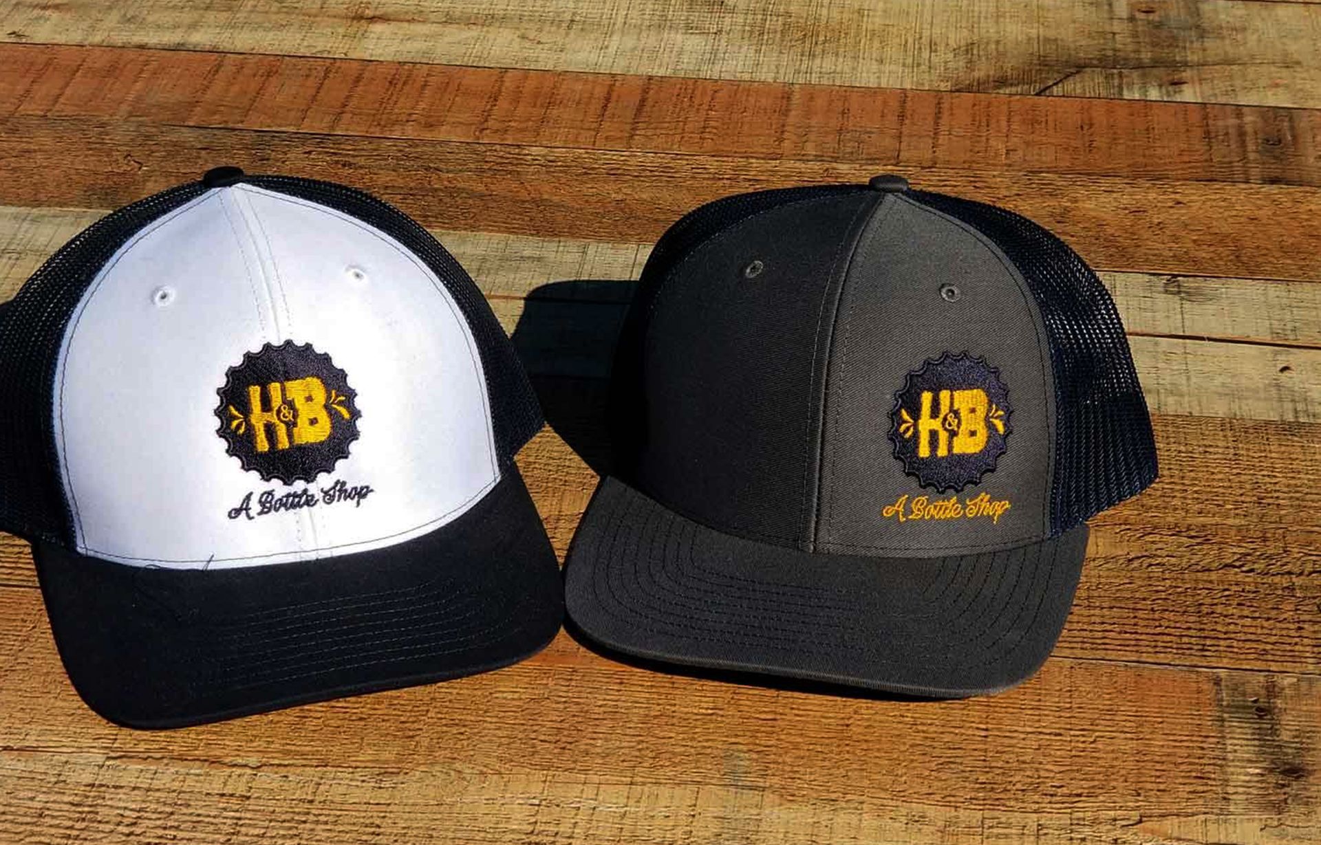 two hats with hb embroidered on them are sitting on a wooden table