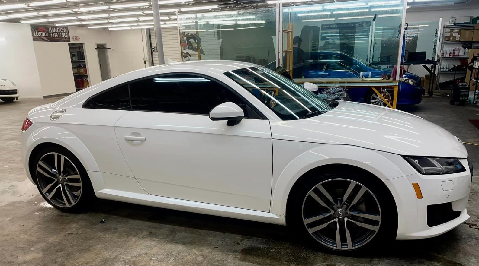 A white audi tt is parked in a garage.
