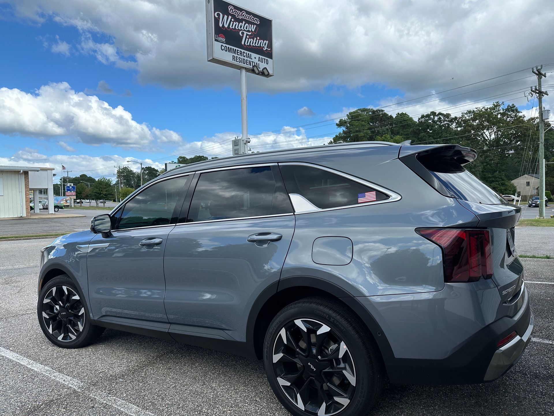 A gray suv is parked in a parking lot in front of a sign.