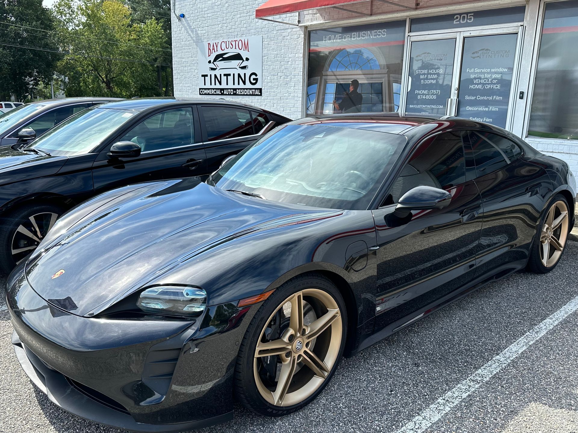 A black sports car is parked in a parking lot in front of a building.
