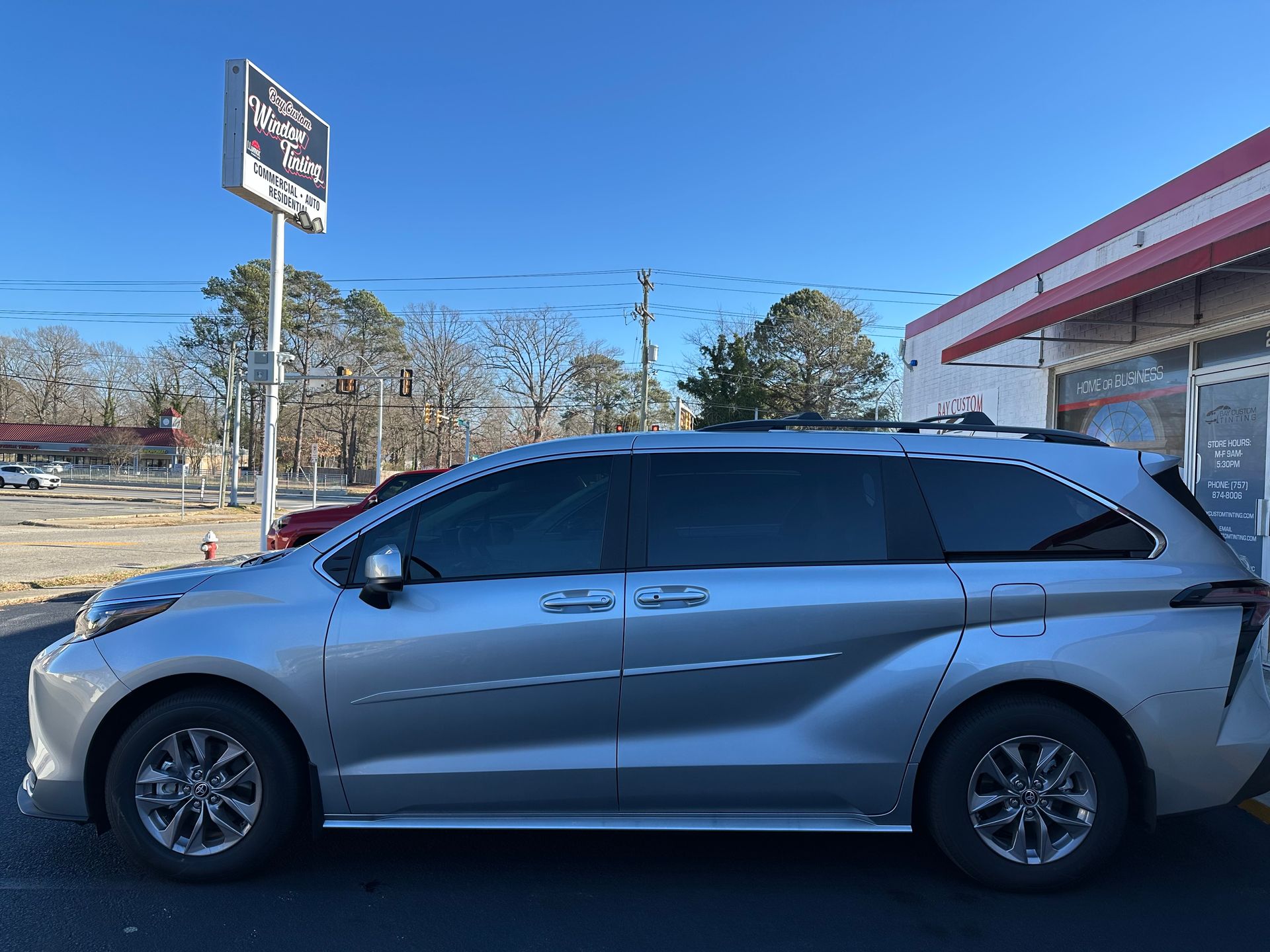 A silver minivan is parked in front of a building.