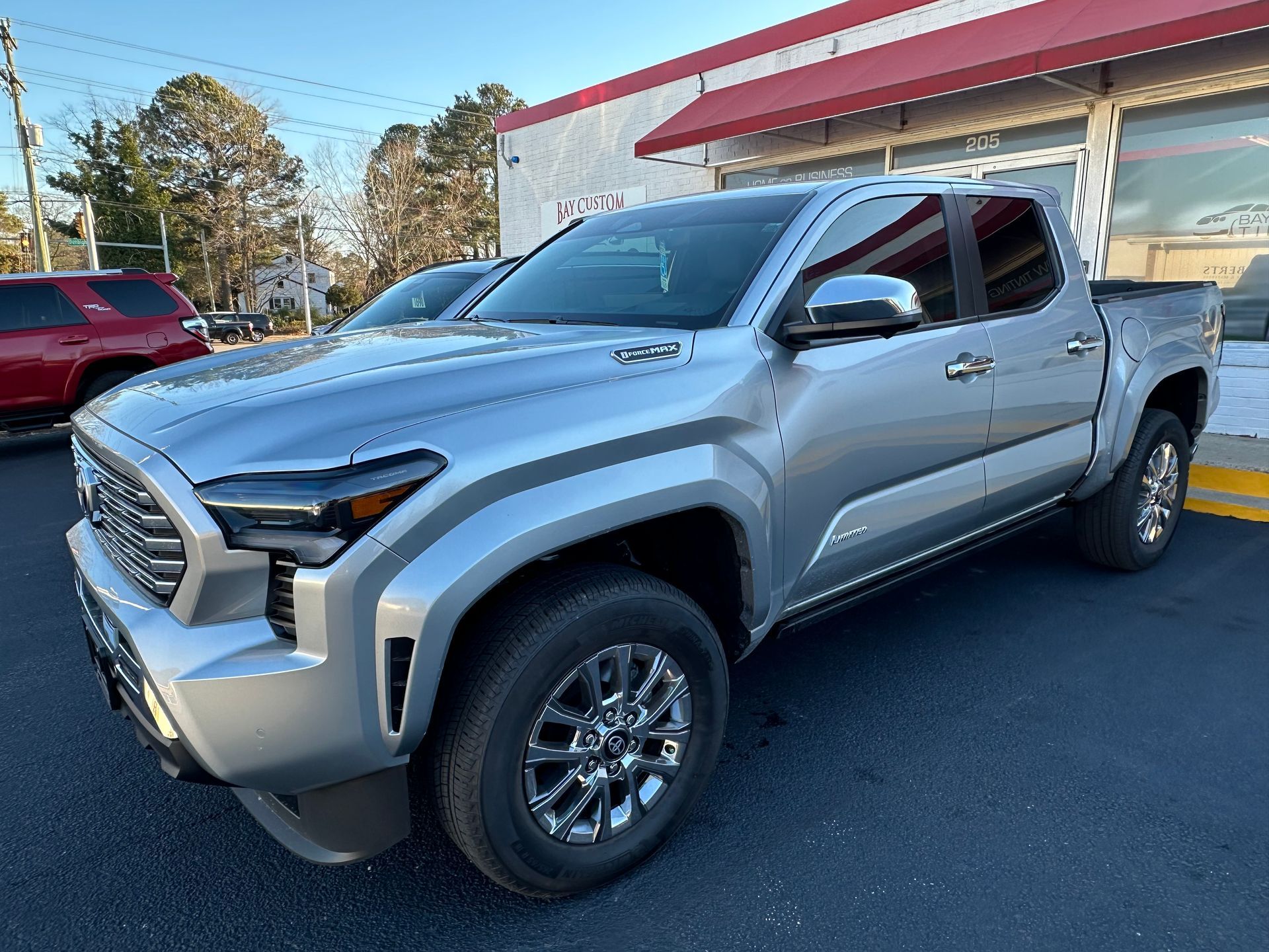 A silver toyota tacoma truck is parked in front of a building.