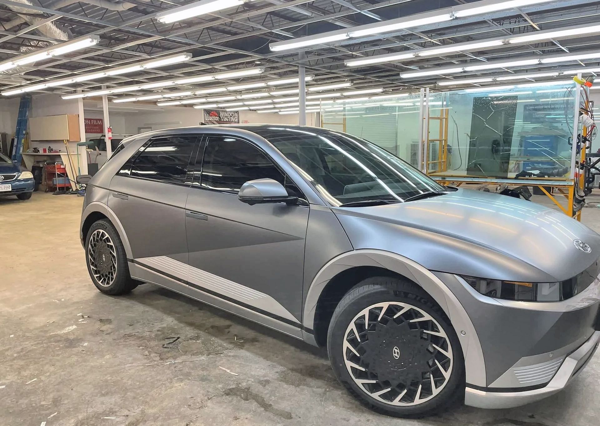 A gray electric car is parked in a garage.