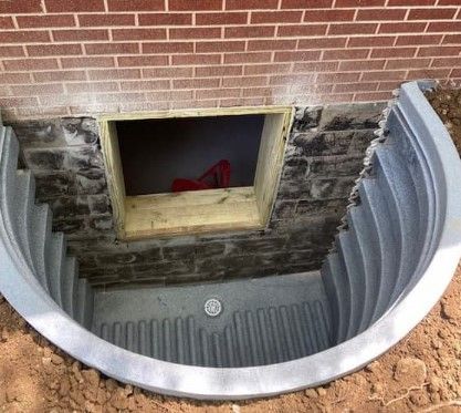There is a window in the basement of a brick building.