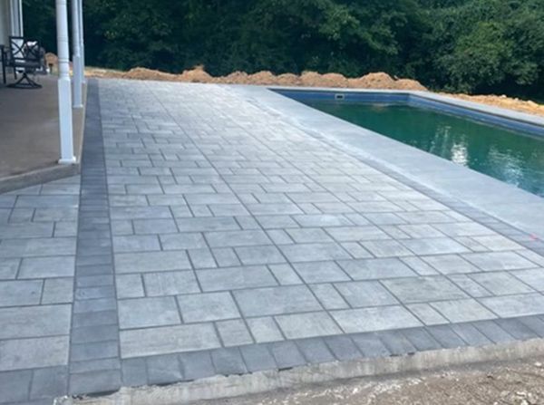 A large swimming pool with a patio in front of it