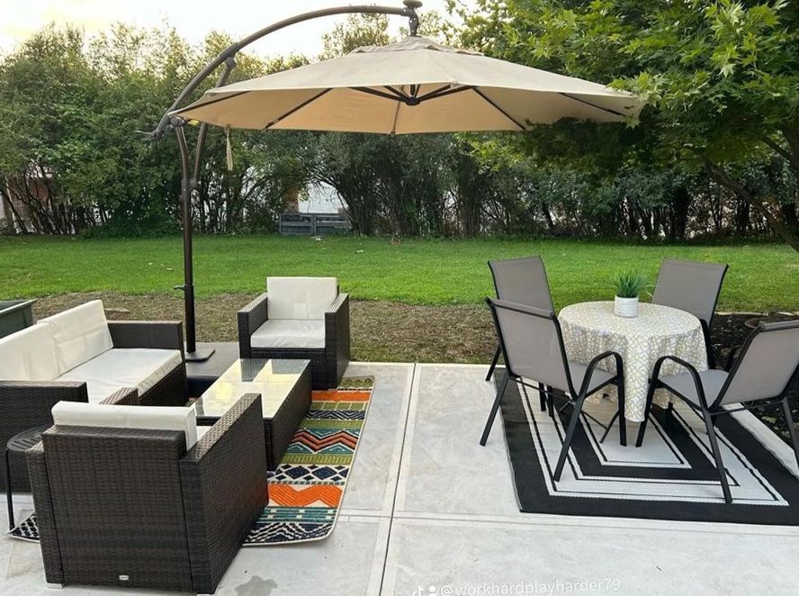 A patio with a couch , chairs , table and umbrella.