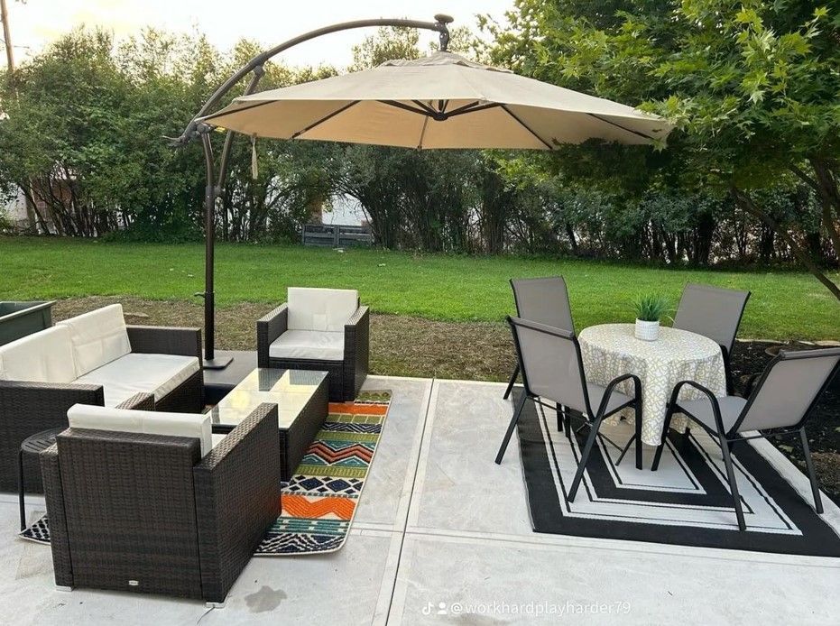 A patio with a couch, chairs, table and umbrella.