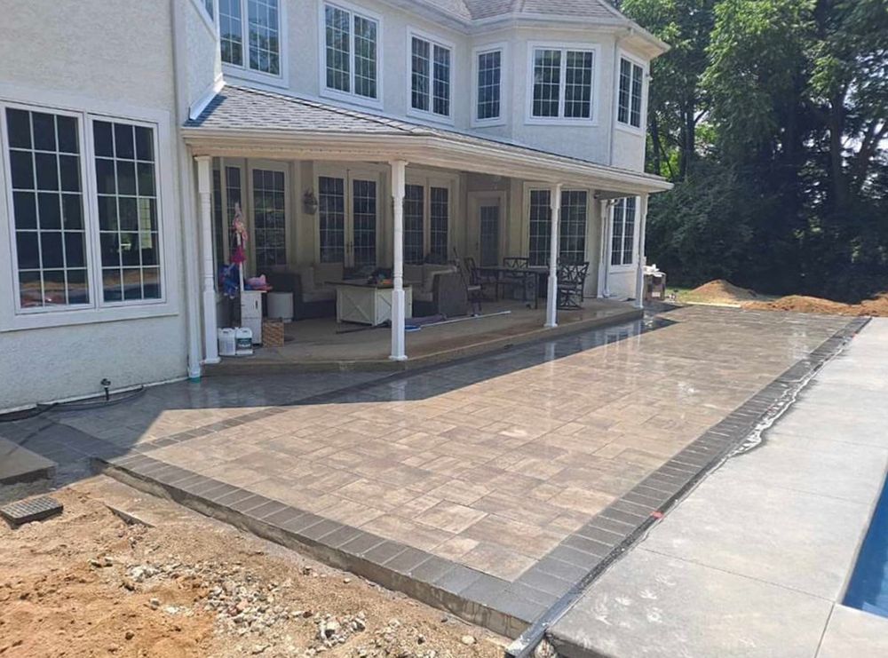 A large white house with a patio and a pool in front of it.