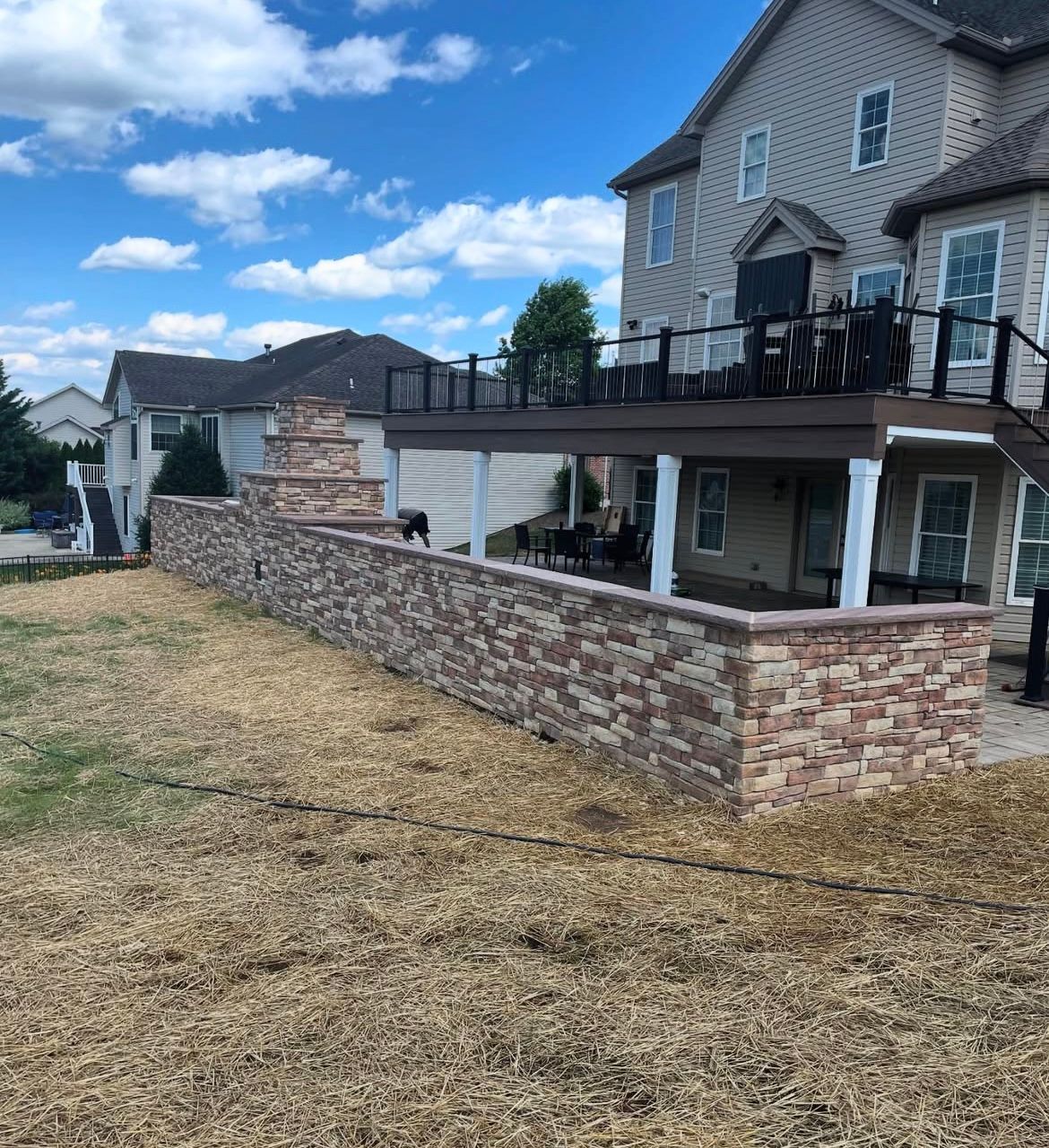 A large house with a deck and a stone wall