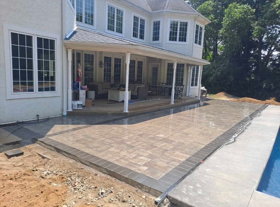 A large white house with a patio and a pool in front of it.