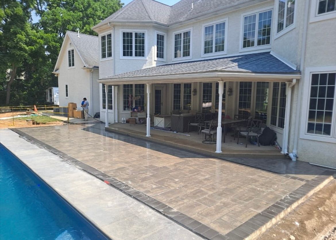 A large white house with a patio and a pool in front of it.