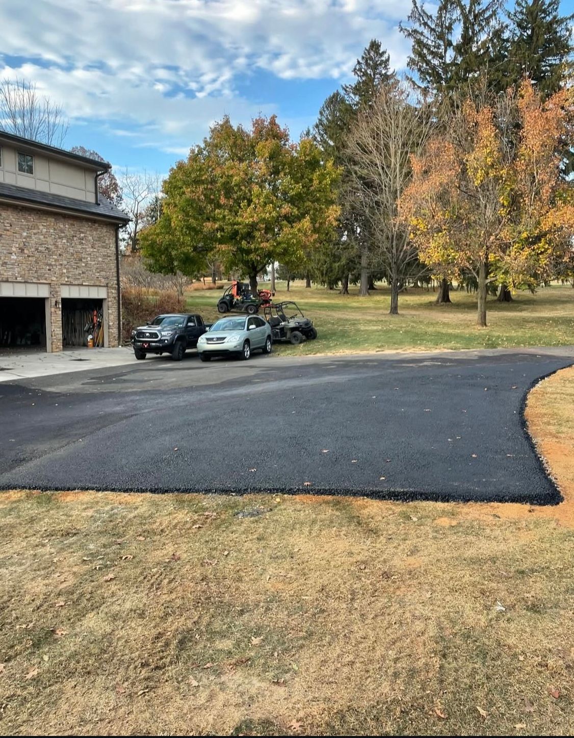 A driveway with cars parked in front of a house.