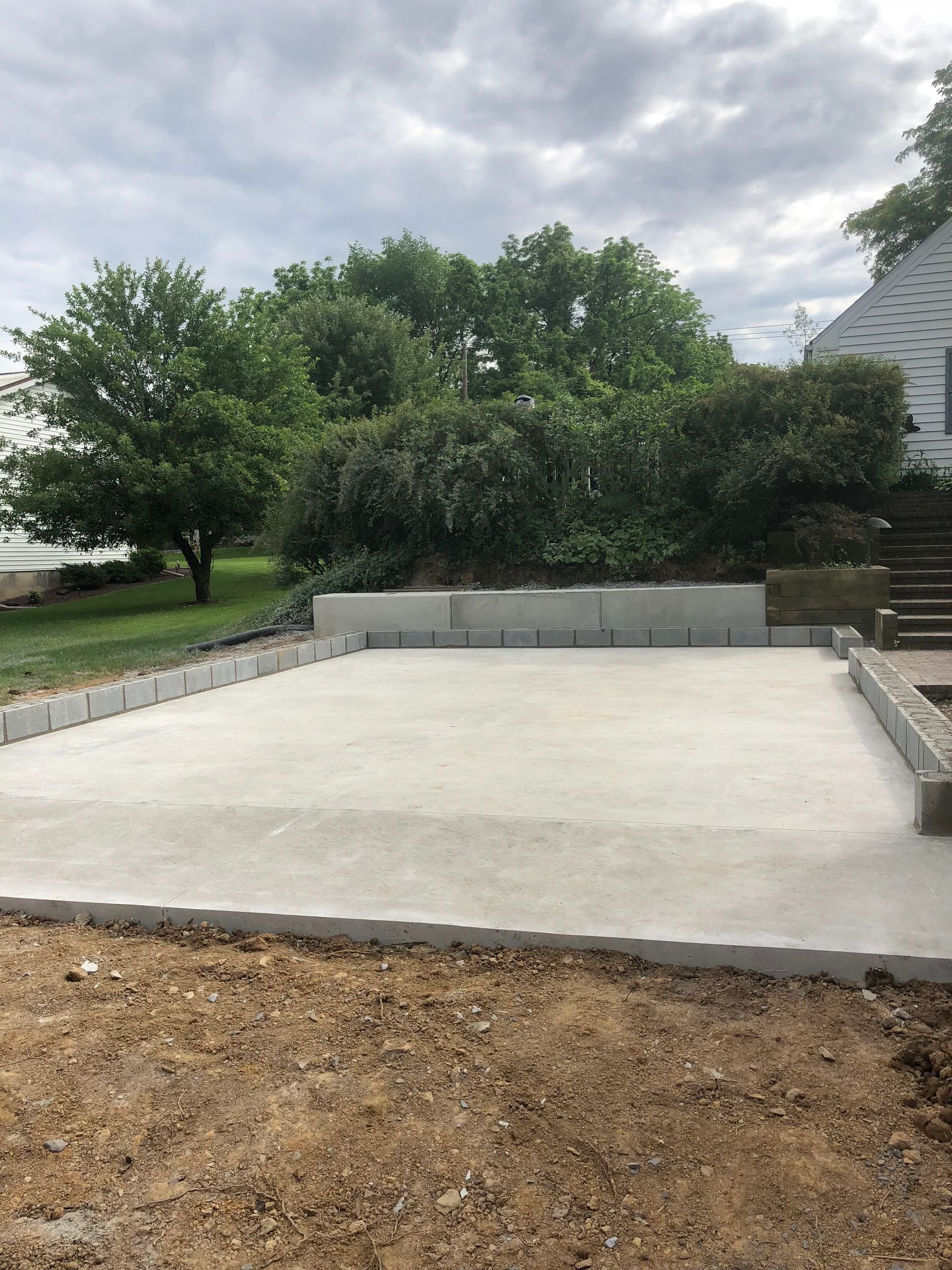 A concrete foundation is being built in the backyard of a house.