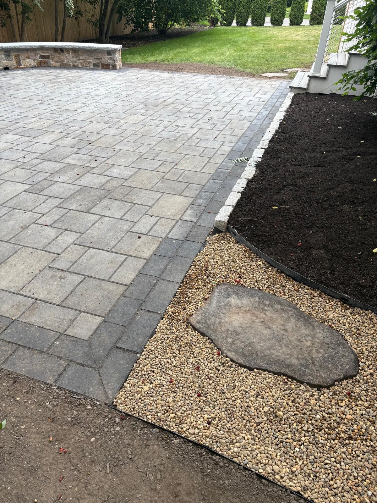 Paver walkway beside mulch bed and gravel edging in a landscaped yard