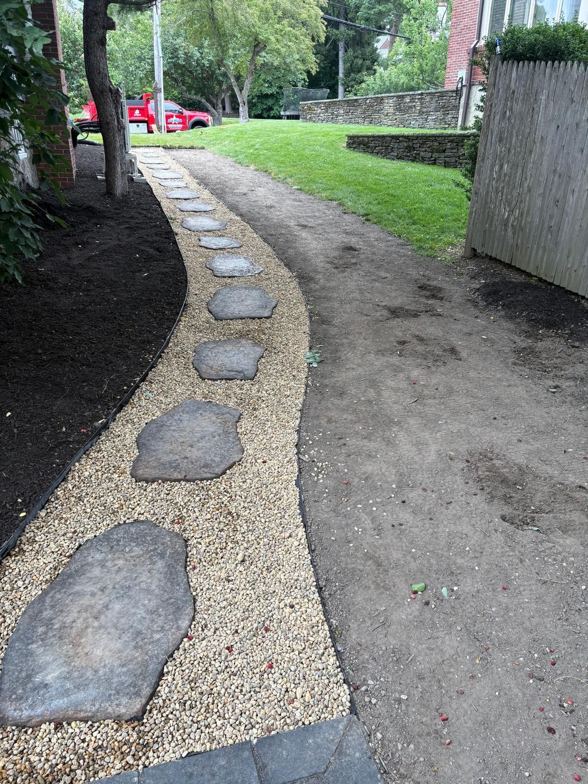 Curved gravel path with stepping stones beside grass and trees in a park