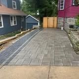 Paver driveway beside houses, leading to a wooden gate at the end.