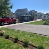 Suburban street with a red pickup truck parked by a house and landscaped lawn on a sunny day