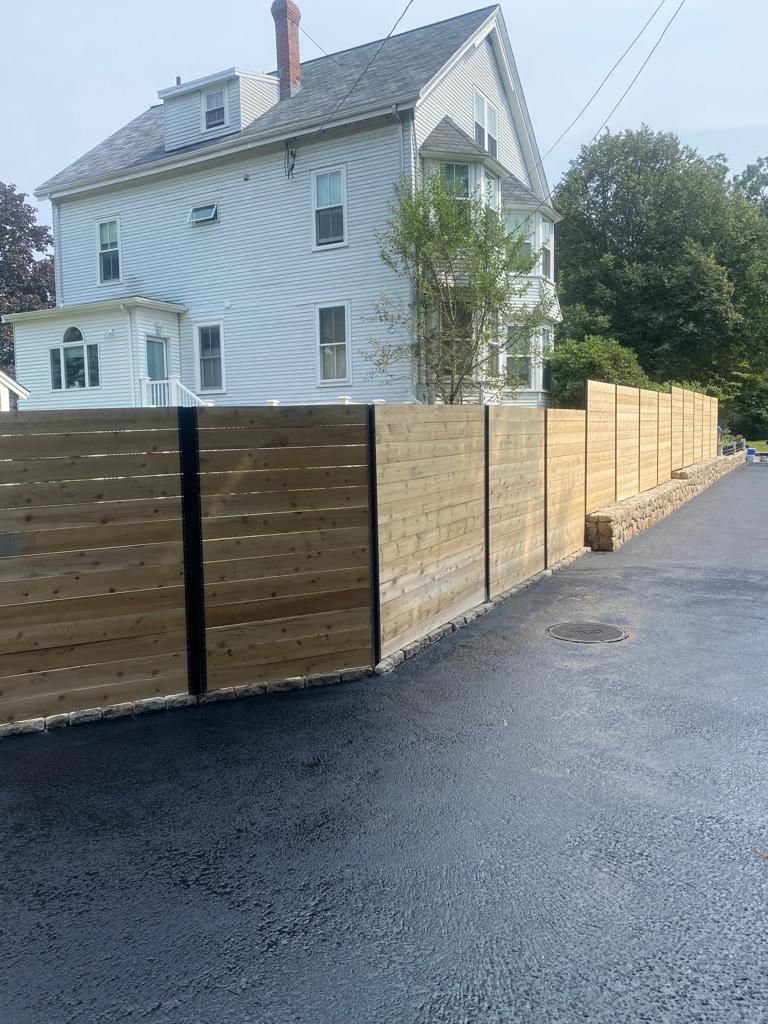 White house behind wooden construction fence along a wet street on an overcast day