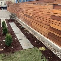 Modern side yard with wood privacy fence, concrete stepping stones, mulch beds, and small shrubs
