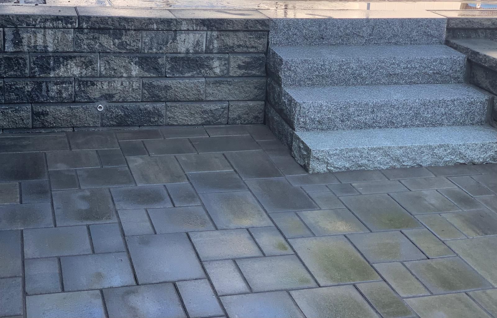 Stone patio with steps leading up to a raised wall and doorway landing