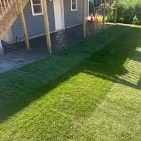 Backyard lawn with a house deck and strong diagonal shadows from a fence or railing