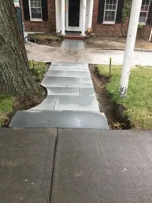 Front walkway with newly laid gray pavers leading to a brick house entrance
