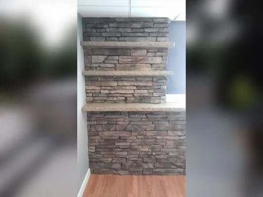 Stone-faced wall with built-in shelves in a room with white walls and wood floor