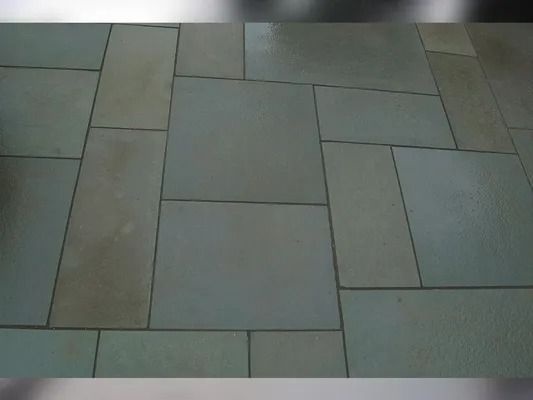 Rectangular stone floor tiles in muted gray and beige, arranged in a staggered pattern.