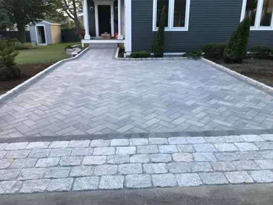 Stone-paved driveway leading to a house entrance with dark blue siding and white trim
