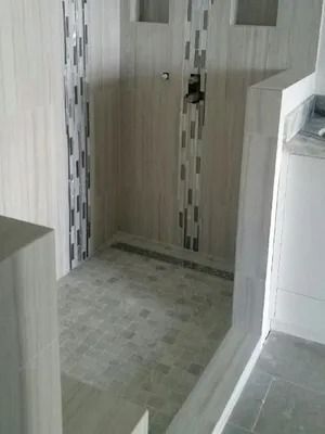 Small tiled bathroom corner with a shower floor and a door or partition in the back.