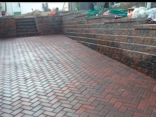 Brick-paved courtyard with raised stone retaining walls and steps in the background
