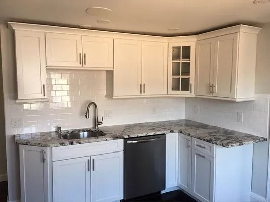 White corner kitchen with granite countertops, subway tile backsplash, stainless sink, and dark dishwasher.