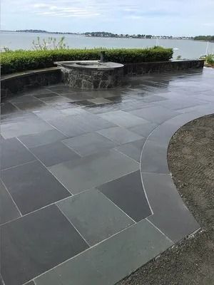 Curved stone patio with a low wall and a waterfront view under a cloudy sky