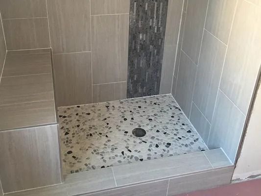 Tiled walk-in shower with a stone-look shower floor and central drain