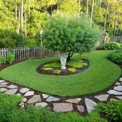 Curved garden bed with a small tree, bordered by stone pavers and surrounded by lush green lawn.