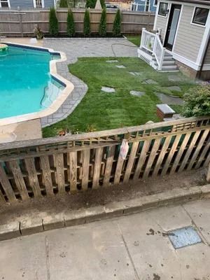 Backyard pool beside a small grassy patio and wooden fence at a townhouse complex