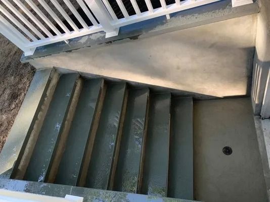 Concrete stairwell with gray steps and a white railing in a narrow indoor space