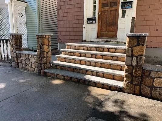Front steps with stone railings leading to a wooden front door of a house