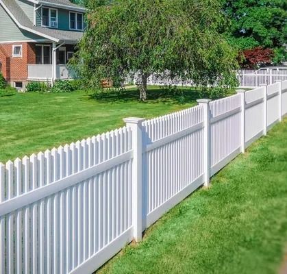 White vinyl fence along a green suburban lawn beside a house and a leafy tree