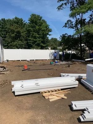 Construction site with stacked white boards, tools, and a fence under a clear blue sky