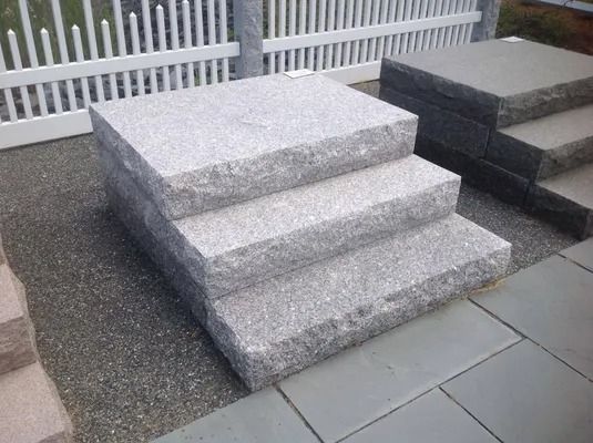 Granite steps leading to a white fence beside a paved walkway