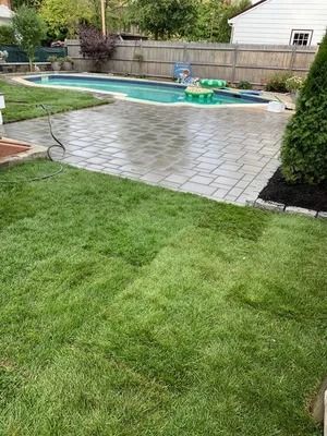 Backyard patio with a swimming pool, green lawn, and a small inflatable pool toy