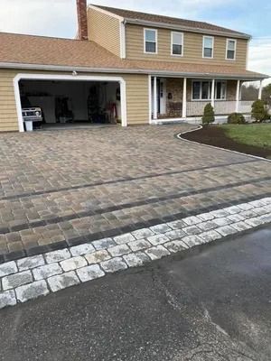 Suburban house with open garage, tan siding, and a paved driveway leading to the street