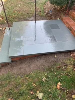 Glossy gray tile platform beside brick steps in a grassy yard