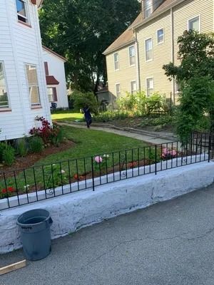 Residential front yard with a child walking on a path beside white and yellow houses.