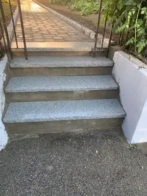 Concrete steps leading to a tiled walkway with metal railings on both sides