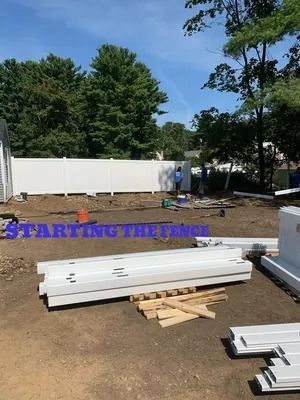 Construction site with stacked white boards and lumber beside a white fence, “STARTING THE FENCE” text on screen.