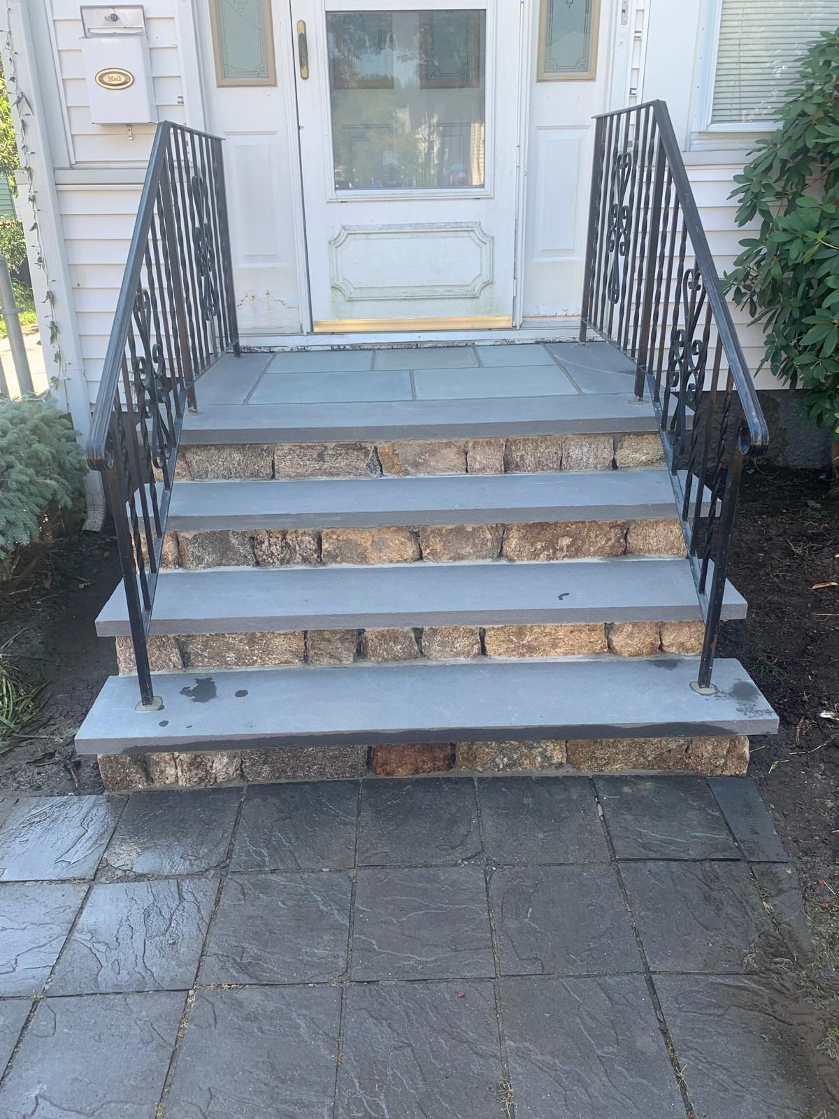 Front steps of a white house with blue railings and a glass-paneled door.
